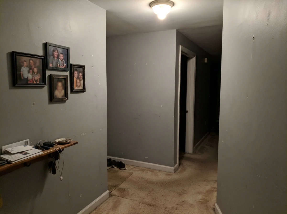 Dim windowless hallway with beige carpet showing Boothbay Gray looking dull and muddy.