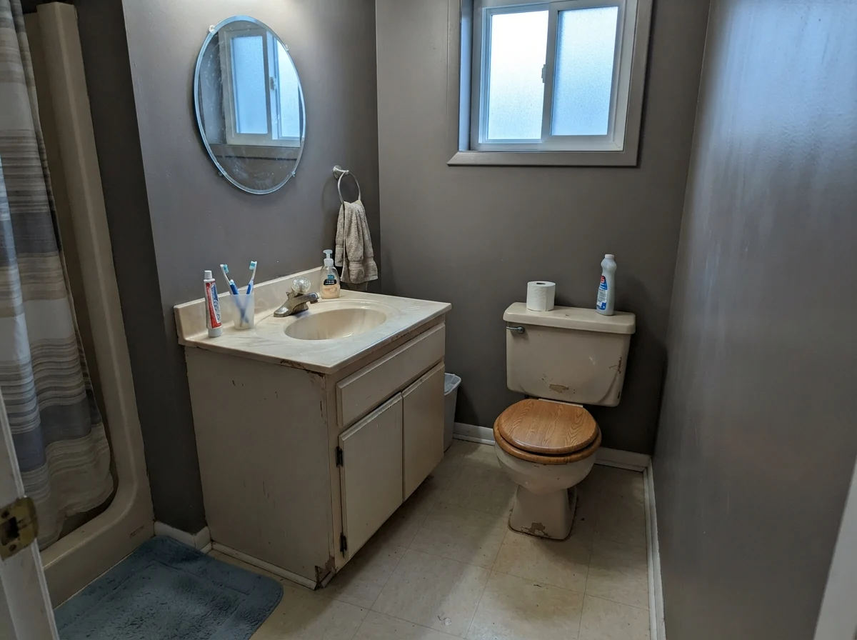 Dated bathroom showing Chelsea Gray picking up a cool cast next to a beige vanity.