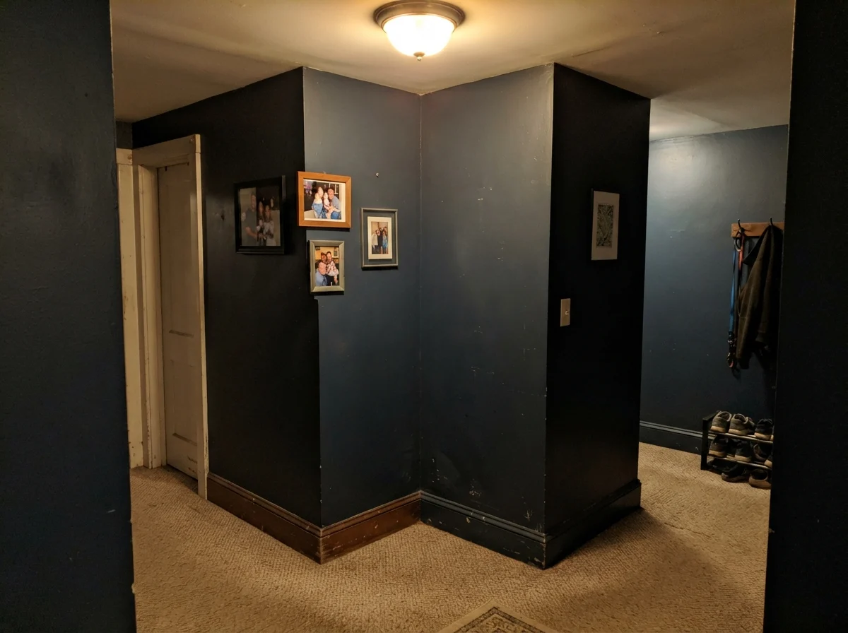Dim windowless hallway corner showing Hale Navy looking muddy and near-black under poor lighting.
