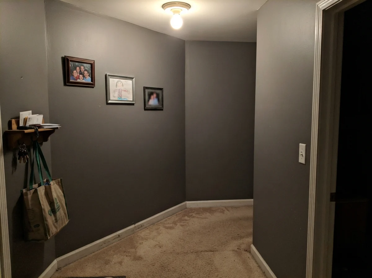 Dim windowless hallway showing Kendall Charcoal looking flat, muddy, and dark.