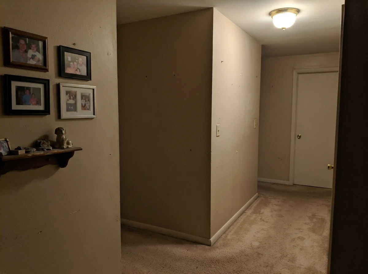 Dim windowless hallway corner showing Manchester Tan looking flat, muddy, and drab