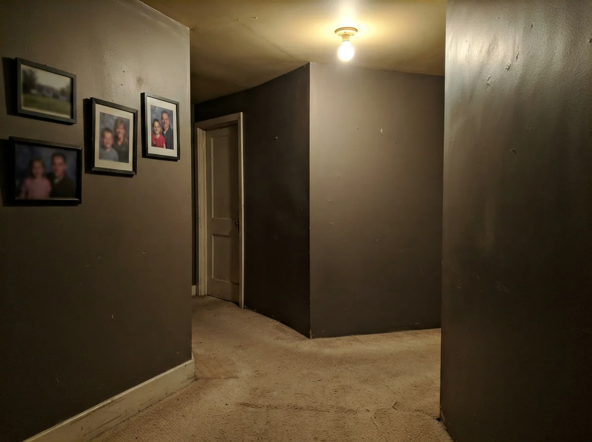 Dim windowless hallway corner showing painted walls looking flat, muddy, and putty-like under poor lighting.
