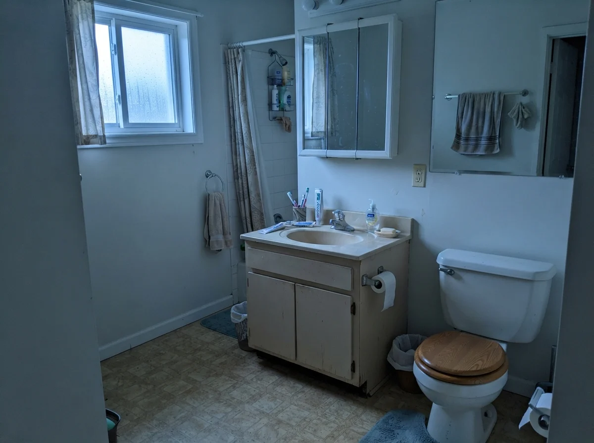 Modest bathroom with older beige vanity and Simply White walls under cool northern daylight.