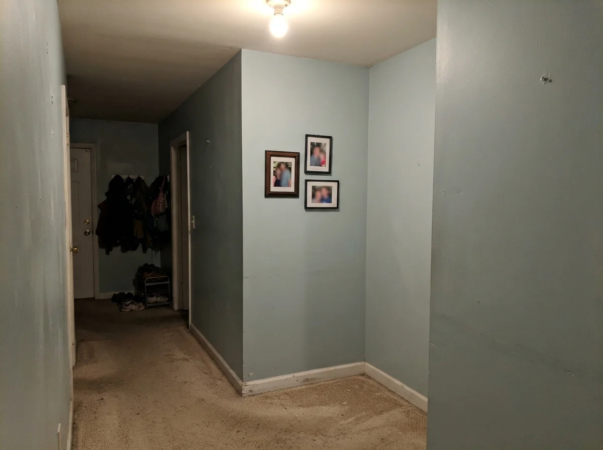 Windowless hallway corner showing Benjamin Moore Smoke looking muddy and gray under dim lighting