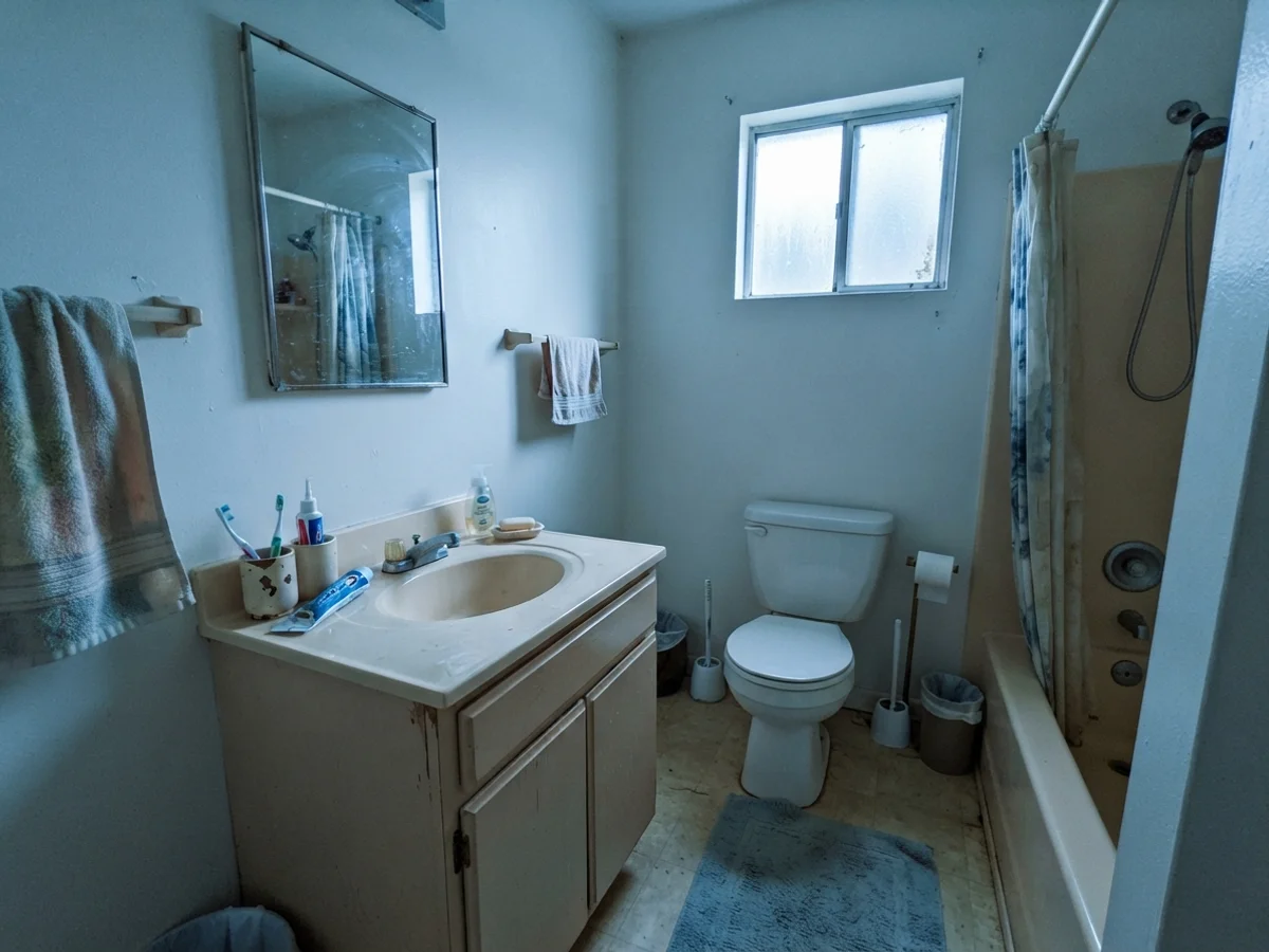 Modest bathroom with cool cast on painted walls beside an older beige vanity.