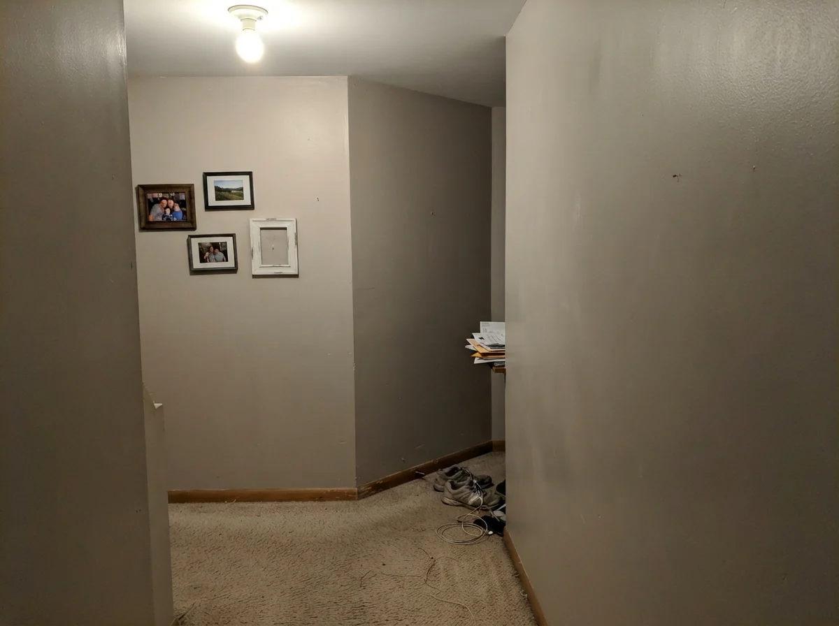 Windowless hallway corner showing painted wall looking flat and muddy under single ceiling bulb.