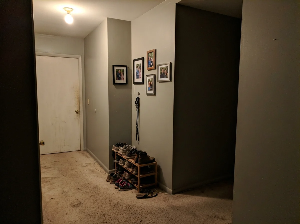 Dim windowless hallway corner where painted wall looks muddy gray under a single ceiling bulb.