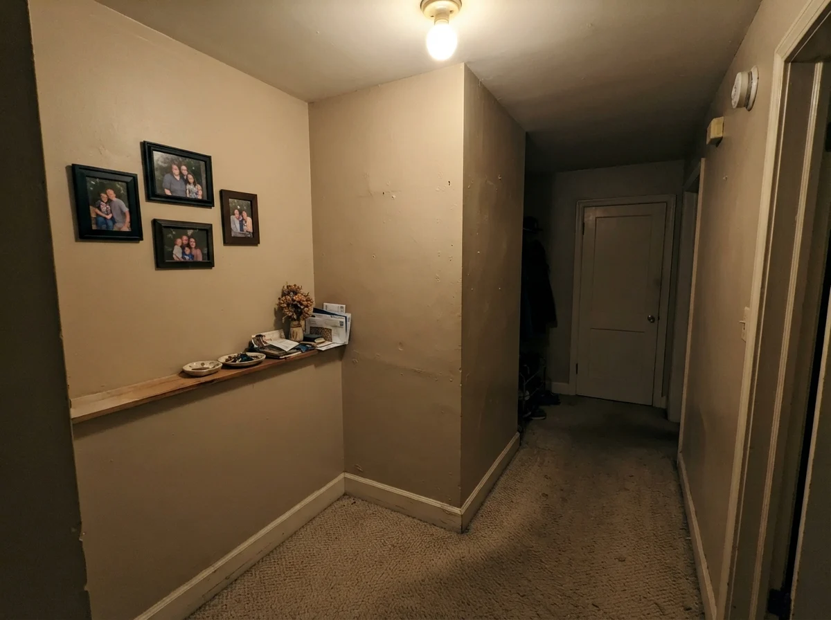 Unflattering view of Kilim Beige in a windowless hallway corner under dim ceiling light looking flat and muddy.