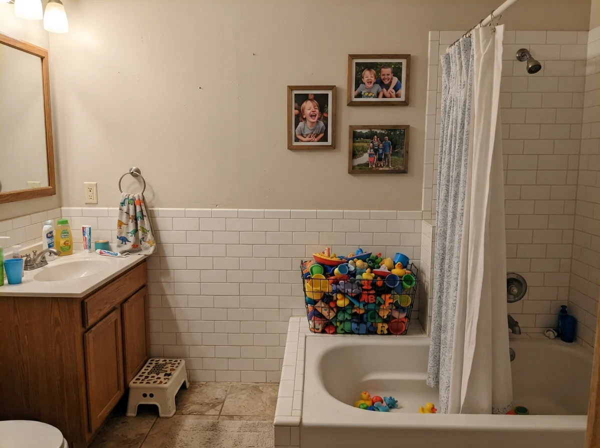 Kids bathroom with painted walls over white subway tile and colorful bath toys.