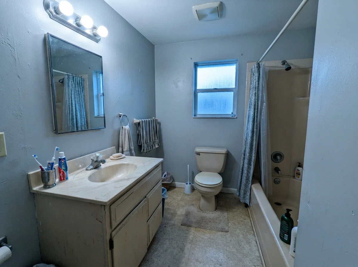 Modest bathroom with cool light hitting painted walls next to a beige vanity.