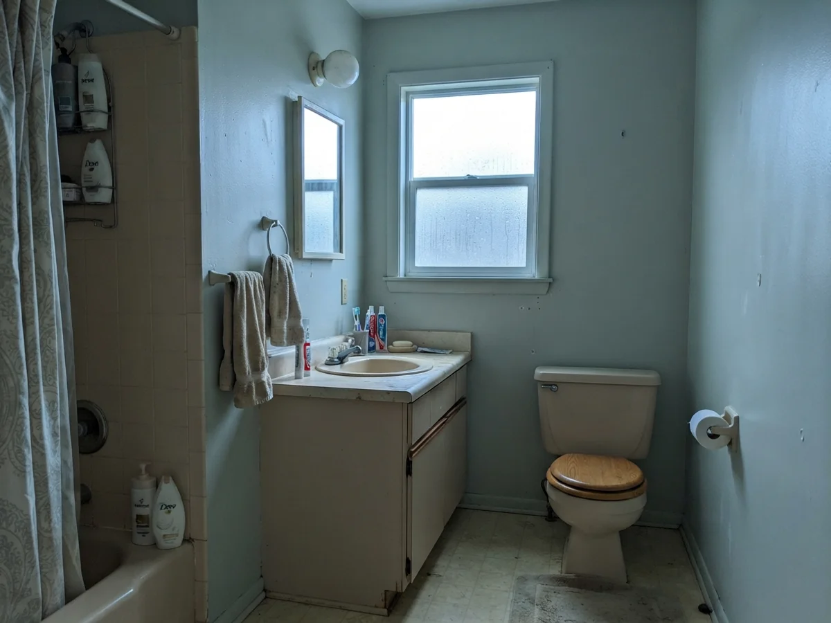 Modest bathroom with painted walls showing cool blue tones next to a beige vanity.